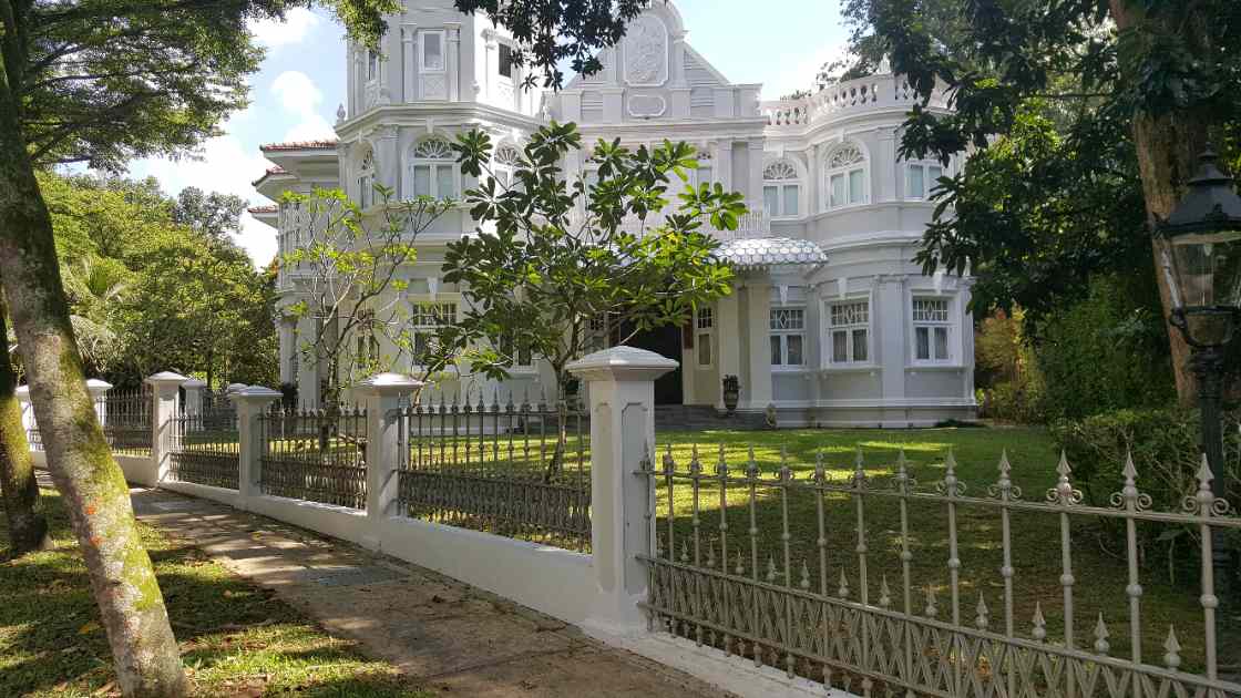 Grand white heritage bungalow in Singapore with a worn natural-grass front lawn before installation