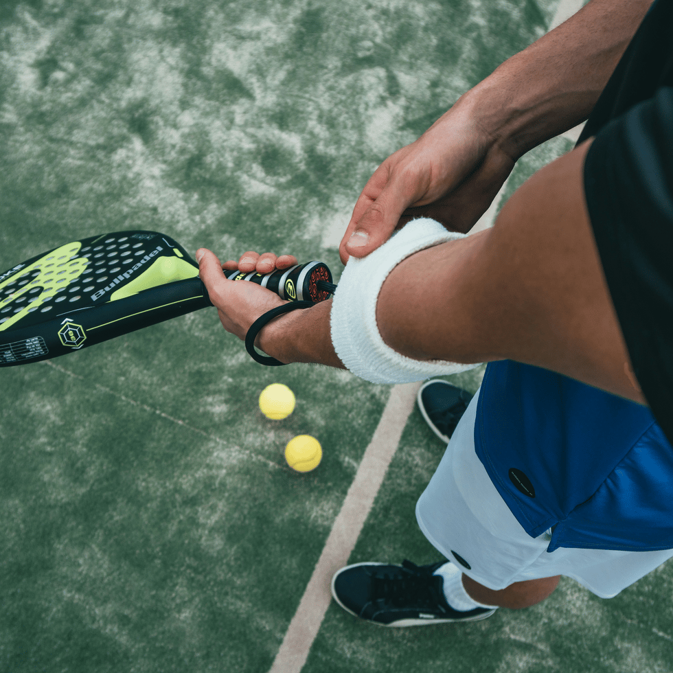 Padel player gripping a racket on a green sand-dressed artificial grass court