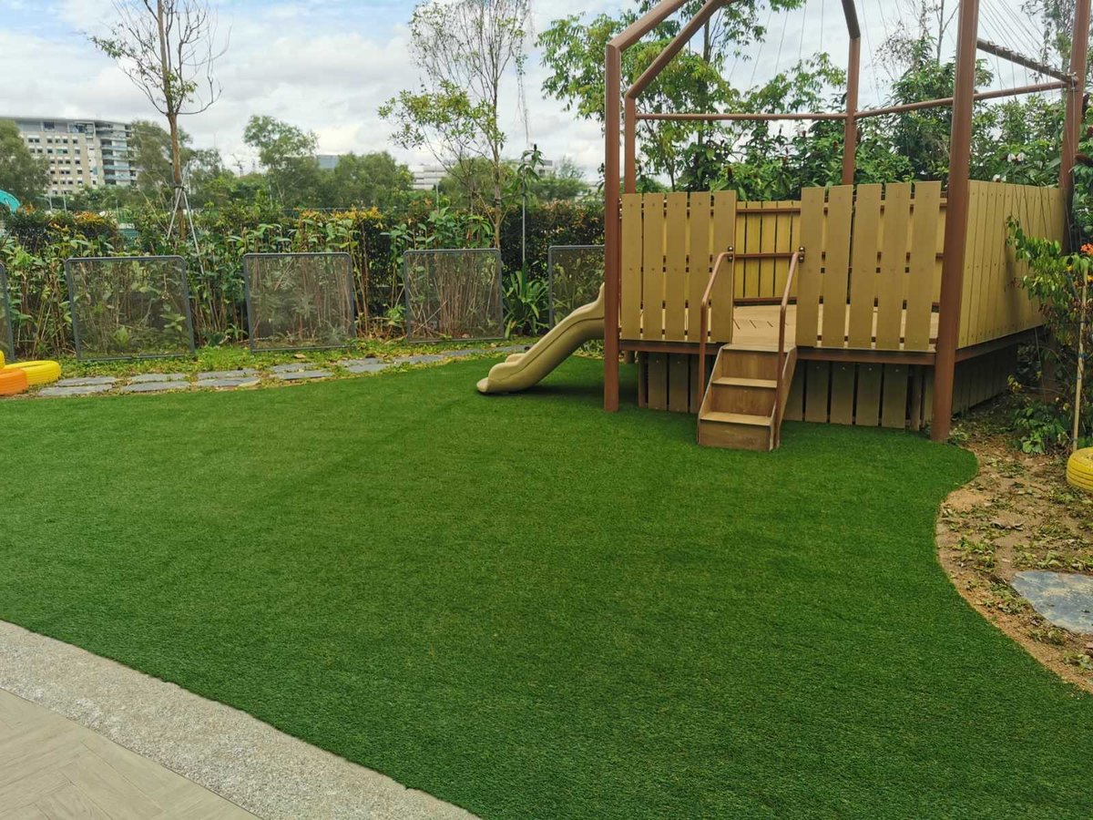 Soft artificial grass childcare play lawn wrapping up to the play structure at NTUC childcare, Punggol