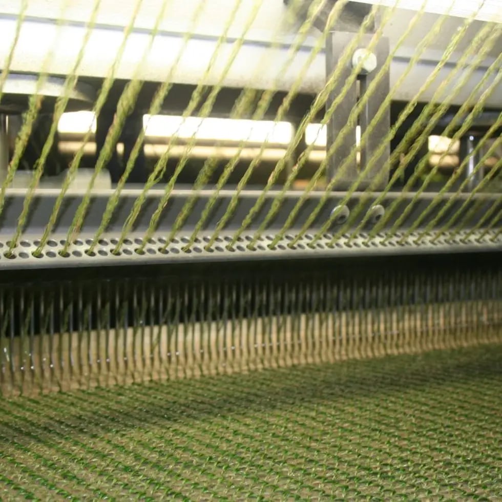 Namgrass artificial grass yarn being tufted into the backing on a precision machine