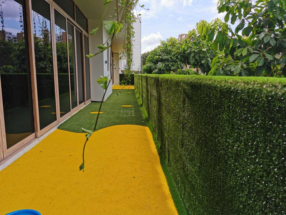Soft artificial-grass wall running along a childcare play corridor at Skool4Kids, Singapore