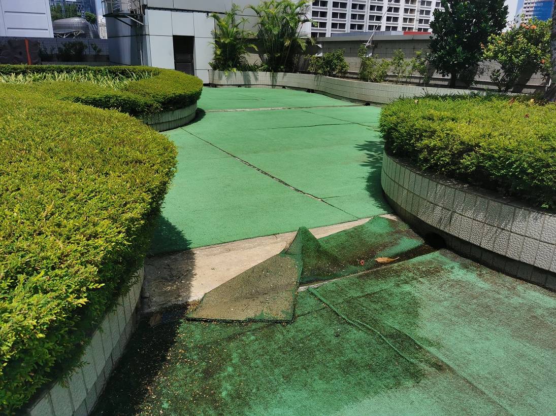 Cheap artificial grass faded, peeling and lifting off a rooftop deck in Singapore