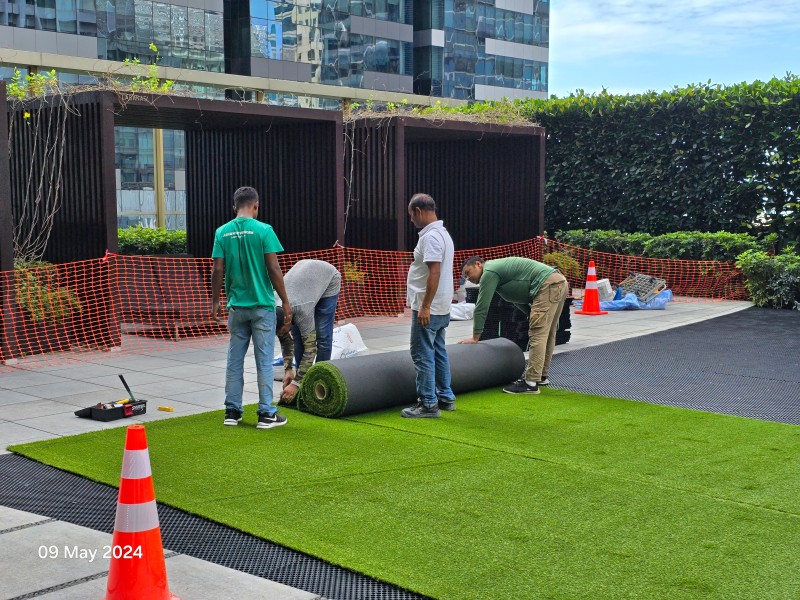 The ibuild team rolling out premium Namgrass turf over the drainage cells at One Shenton, 09 May 2024