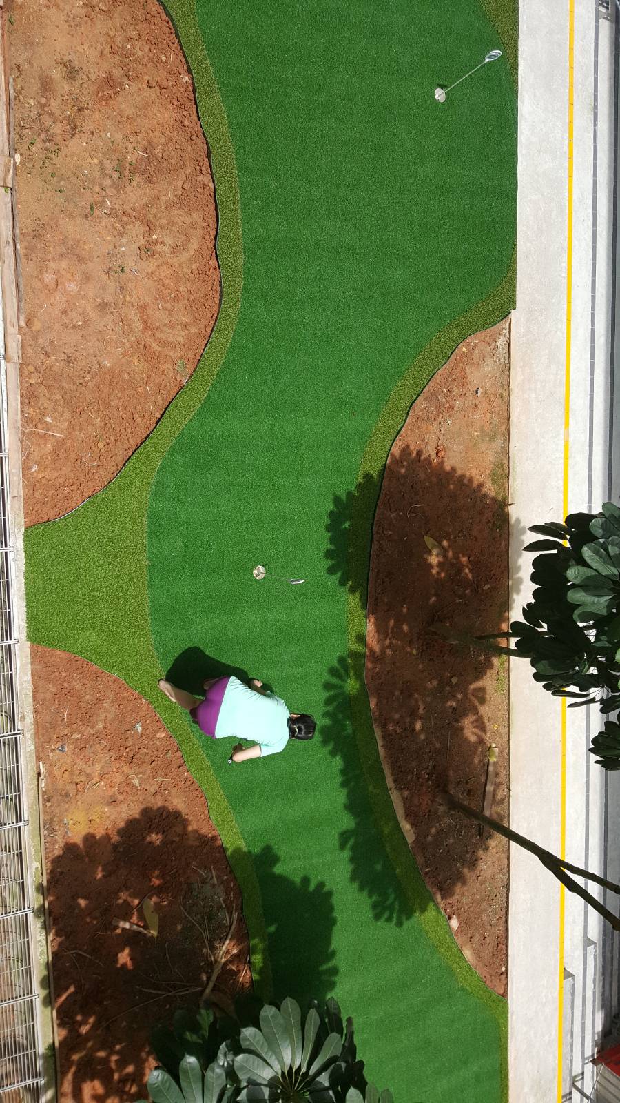 Wave-edged artificial grass lawn beside a timber deck in the eco garden at West Spring Primary School
